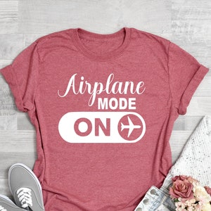 May include: Coral pink t-shirt with the text "Airplane Mode ON" and a white airplane icon.