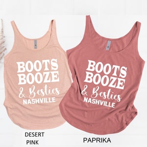 May include: Two tank tops with the text "Boots Booze & Besties Nashville" in white. The tank top on the left is a light pink color and the tank top on the right is a darker pink color.
