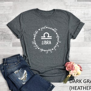 May include: Dark gray heather t-shirt with a white circle graphic featuring the Libra zodiac symbol and the words "just sociable refined fun artistic lovable harmonious".