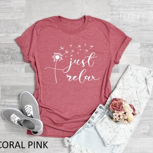 Peut inclure: T-shirt rose corail avec un motif de pissenlit blanc et le texte "just relax".