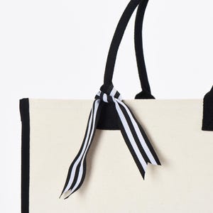 a white bag with a black and white striped bow