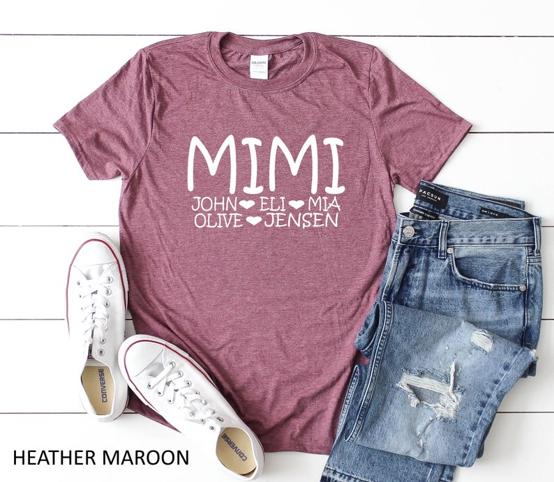 Peut inclure: T-shirt en marron heather avec le texte "MIMI" et les noms "JOHN", "ELI", "MIA", "OLIVE" et "JENSEN" avec des c&oelig;urs entre chaque nom.
