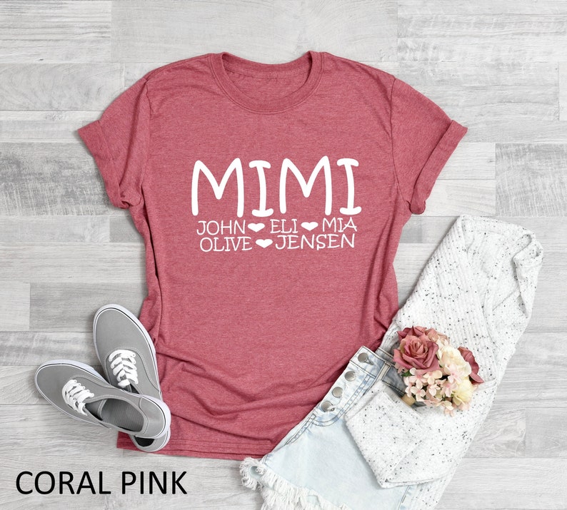Peut inclure: T-shirt rose corail avec le texte "MIMI" et les noms "JOHN OLIVE", "ELI" et "MIA JENSEN" imprim&eacute;s en blanc.