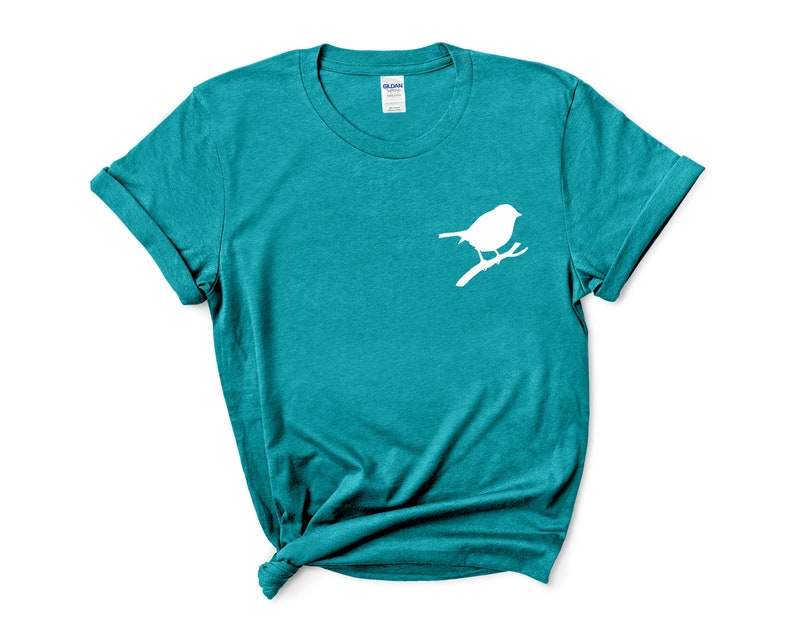 May include: Teal blue t-shirt with a white silhouette of a bird on a branch.