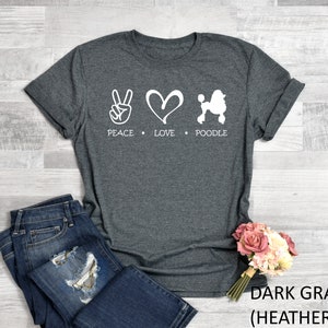 K&ouml;nnte beinhalten: Dunkelgraues T-Shirt mit einem wei&szlig;en Peace-Zeichen, einem Herzen und einem Pudel-Motiv. Der Text "Peace Love Poodle" ist unter dem Motiv gedruckt.