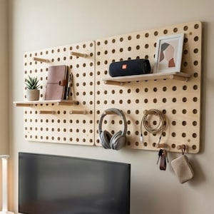 Pu&ograve; includere: Organizzatore da parete in legno con ripiani, contenente una piccola pianta in vaso, un taccuino in pelle marrone, una penna, un altoparlante nero, una foto incorniciata e altri accessori. Un monitor per computer, una tastiera e un mouse sono su una scrivania di legno.