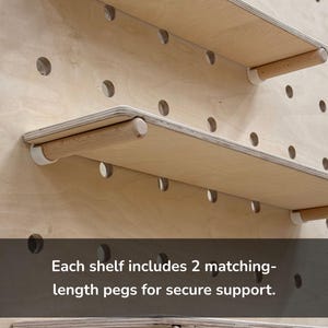 May include: Wooden shelves with matching pegs for secure support. The shelves are made of light-colored wood and are mounted on a pegboard. The text on the image says, "Each shelf includes 2 matching-length pegs for secure support."