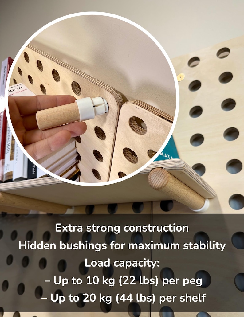 Op de afbeelding: Een lichtgekleurd houten pegboard-wandsysteem met cilindrische houten pinnen en witte bussen. De tekst luidt: Extra strong construction, Hidden bushings for maximum stability, Load capacity: Up to 10 kg (22 lbs) per peg, Up to 20 kg (44 lbs) per shelf.