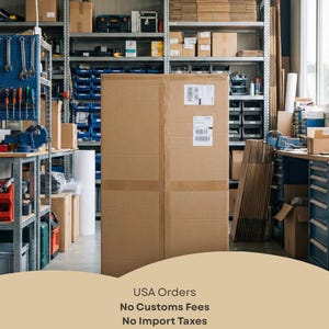 May include: A large, rectangular brown cardboard shipping box stands in the center of a warehouse storage area. The box features two white shipping labels on its front surface. The background shows metal shelving units filled with various boxes and tools.