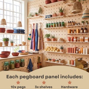 Op de afbeelding: Een lichtgekleurd houten pegboard-wandsysteem met meerdere planken met potten, planten en textiel. De tekst vermeldt dat elk paneel 10 haringen van 12 cm, 3 planken van 45 x 12 cm en hardware voor eenvoudige installatie bevat.