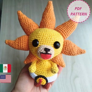 Puede incluir: Un peluche de ganchillo hecho a mano con forma de sol de dibujos animados con una cara sonriente y una lengua roja. El sol tiene secciones amarillas y naranjas, ojos negros y un pañal blanco. Incluye el texto "PDF PATTERN".