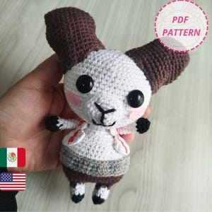 Puede incluir: Un pequeño muñeco amigurumi de ganchillo con forma de carnero, grandes cuernos marrones curvados, cabeza y cuerpo blancos, ojos de botón negros, mejillas rosadas y pezuñas negras. El muñeco lleva un chaleco blanco y una cintura gris. Texto PDF PATTERN.
