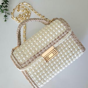 Bolso baguette beige crema: bolso de crochet con asa superior y cadena dorada.