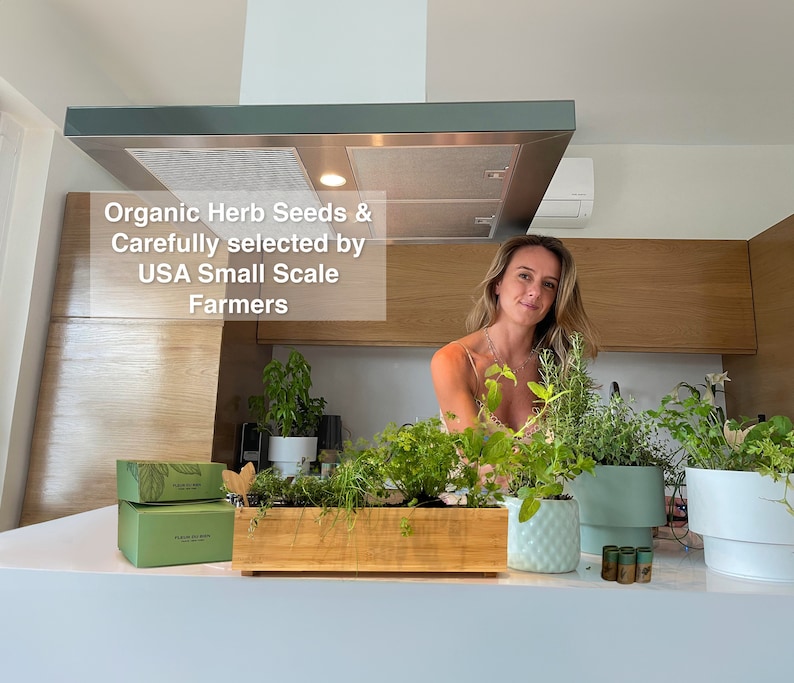 May include: A kitchen scene featuring a woman surrounded by potted herbs and a wooden planter box filled with various green herbs. The text "Organic Herb Seeds & Carefully selected by USA Small Scale Farmers" is visible.