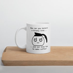 May include: White ceramic coffee mug with a black illustration of a coffee pot with a face. The text reads "How can you balance a binary tree... ...and not know how to make coffee?"