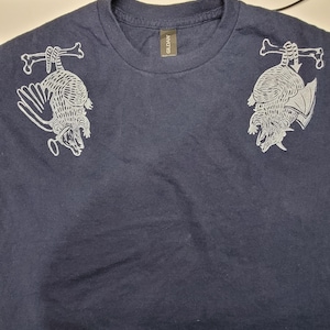 May include: A navy blue t-shirt with a white graphic print of two armadillos hanging from bones. The shirt has a Gildan brand tag.