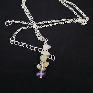 May include: A silver chain necklace with a pendant made of stacked semi-precious stones. The stones are purple, yellow, green, and pink.