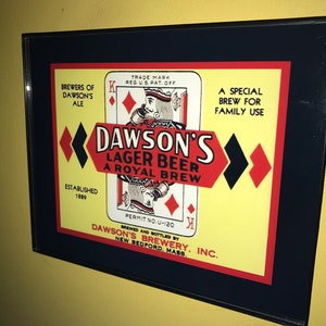 May include: A vintage framed advertisement for Dawson's Lager Beer, a royal brew. The ad features a playing card with the King of Diamonds and the text "Dawson's Lager Beer, A Royal Brew". The ad also includes the text "Brewers of Dawson's Ale, Established 1889, Brewed and Bottled by Dawson's Brewery, Inc., New Bedford, Mass."