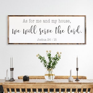 May include: A wooden sign with the text "As for me and my house, we will serve the lord. Joshua 24:15" hanging on a white wall above a wooden dining table with chairs.