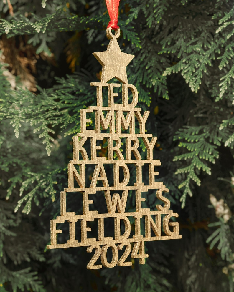 May include: Gold wooden Christmas tree ornament with the names Ted, Emmy, Kerry, Nadia, Lewis, Fielding and the year 2024.