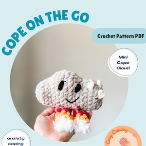 May include: A crocheted cloud-shaped toy with a smiling face, red, orange, and white accents, and the text "COPE ON THE GO." The image also includes the text "Crochet Pattern PDF," "Mini Cope Cloud," and "anxiety coping skill."