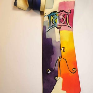 May include: A yellow silk tie with a colorful abstract design featuring a musical instrument and a conductor's baton.