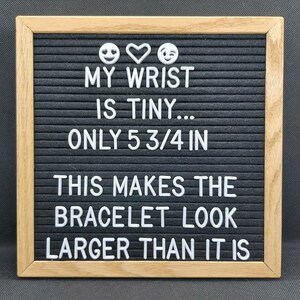 May include: A black letter board with a white wooden frame. The board displays the text "MY WRIST IS TINY... ONLY 5 3/4 IN THIS MAKES THE BRACELET LOOK LARGER THAN IT IS".