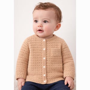 May include: A tan crochet cardigan with a small pocket on the chest. The button-down sweater has long sleeves and white buttons. The baby is wearing blue jeans.