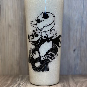 May include: White glitter tumbler with a black and white image of Jack Skellington from The Nightmare Before Christmas.