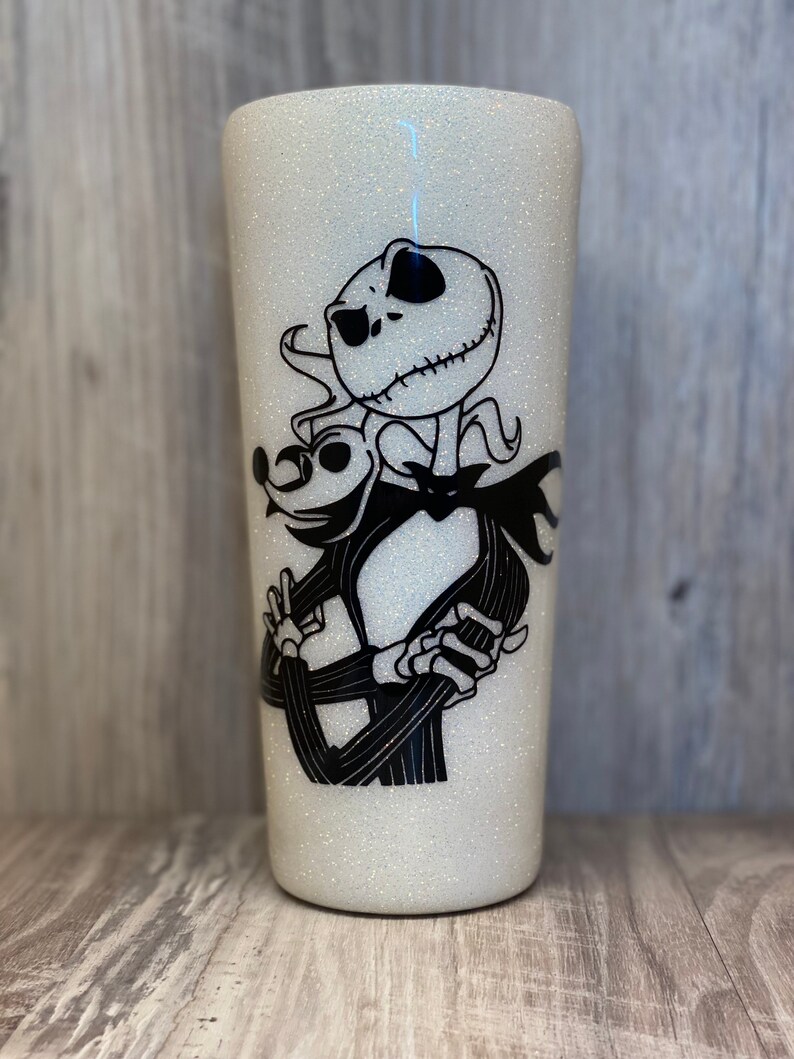 May include: White glitter tumbler with a black and white image of Jack Skellington from The Nightmare Before Christmas.