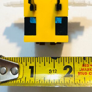 May include: A yellow and black bee-shaped Minecraft figure with blue eyes. The figure is about 1 inch tall.