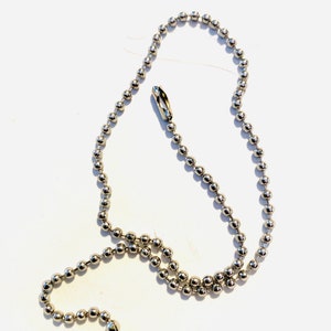 May include: A silver ball chain with two clasps. The chain is made of small, round metal beads.