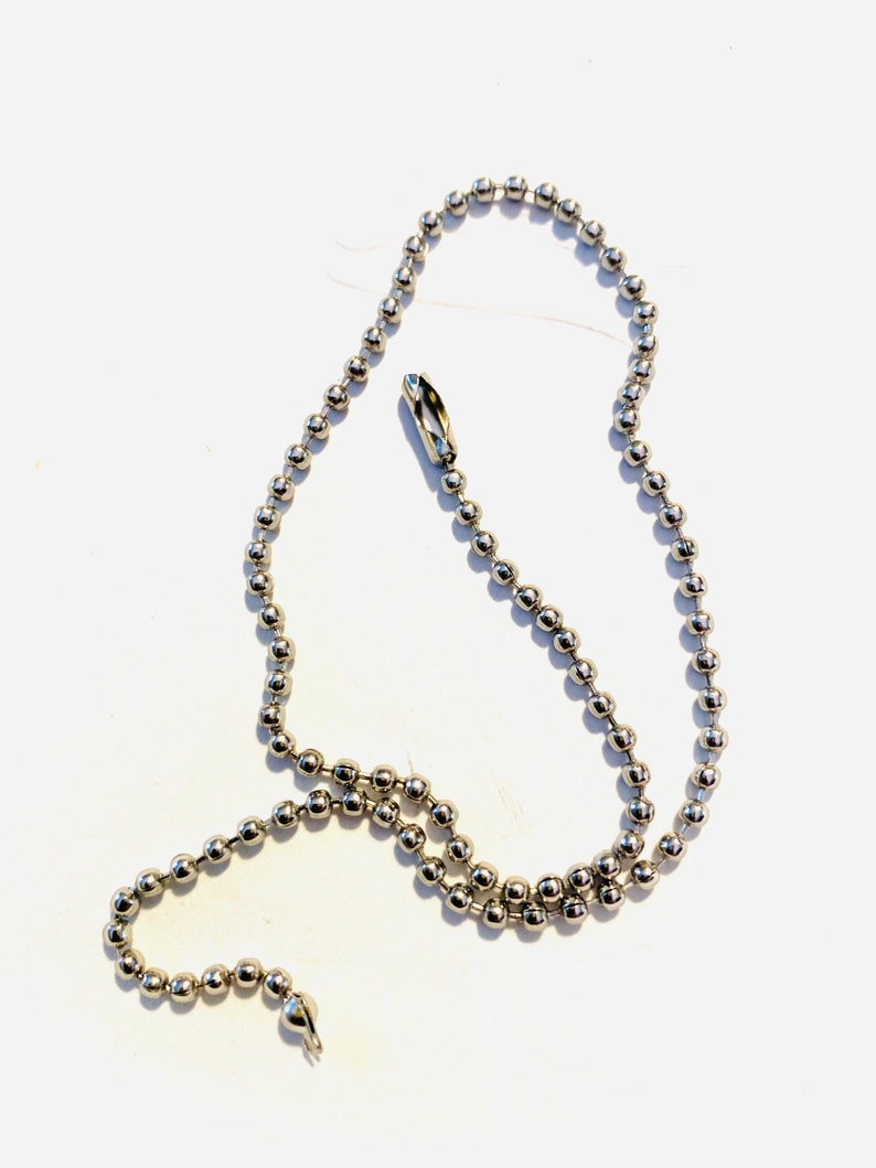 May include: A silver ball chain with two clasps. The chain is made of small, round metal beads.