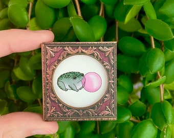 Tiny toad blowing a bubble in a vintage frame