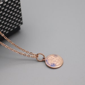 May include: A rose gold chain necklace with a round pendant featuring a detailed image of Saint Michael the Archangel. The pendant has the words "Saint Michael" inscribed around the edge.