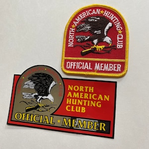 May include: Two red and gold patches featuring an eagle and rifle design. The text on the patches reads "North American Hunting Club" and "Official Member".