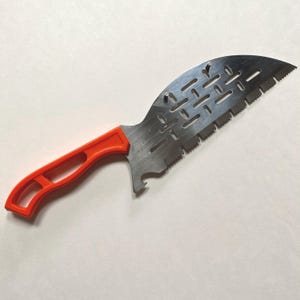 Peut inclure: Un outil de jardinage rouge et argenté avec un bord dentelé et une poignée. L'outil a un petit trou dans la lame.