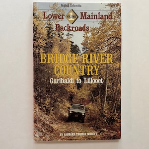 May include: Book cover with a photo of a car driving on a road through a forest. The title is "Bridge River Country" and the subtitle is "Garibaldi to Lillooet". The book is part of a series called "Lower Mainland Backroads, Volume 1".