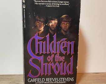 Puede incluir: Un libro de bolsillo titulado "Children of the Shroud" de Garfield Reeves-Stevens. La portada presenta tres figuras con ojos brillantes y el título en letras moradas y doradas. También es visible una cita del Toronto Star.