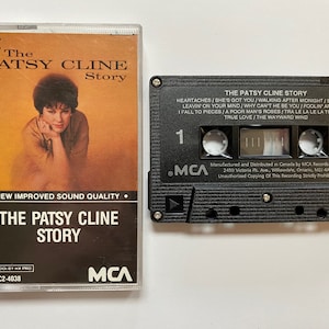 May include: A black cassette tape with the title "The Patsy Cline Story" and a picture of Patsy Cline on the front. The cassette tape is labeled MCA and has the catalog number MCAC2-4038.