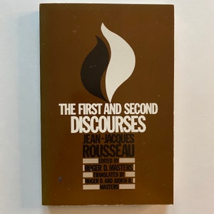 May include: A brown book cover with the title "The First and Second Discourses" by Jean-Jacques Rousseau. The book cover features a black and white flame design.