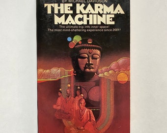 May include: A book cover with a dark background and a colorful illustration of a Buddha figure. The title of the book is "The Karma Machine" and the subtitle is "A Tale of Cybernetic Buddhism by Michael Davidson".