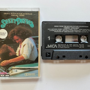 Peut inclure: Une cassette audio noire avec le titre "Sweet Dreams" et le texte "Music from the Motion Picture Soundtrack" imprimé sur le devant. La cassette est étiquetée "MCAC 39301".
