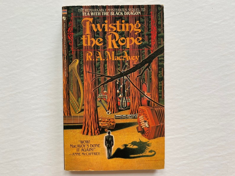 Puede incluir: Una portada de libro con fondo amarillo y una escena de bosque. El t&iacute;tulo "Twisting the Rope" est&aacute; en una fuente grande y estilizada. El nombre del autor, "R.A. MacAvoy", est&aacute; debajo del t&iacute;tulo. La portada presenta una soga para ahorcar, un arpa, un viol&iacute;n y una concertina. El texto "WOW! MacAVOY'S DONE IT AGAIN!" est&aacute; en la parte inferior de la portada, con el nombre del autor, "ANNE MCCAFFREY", debajo.