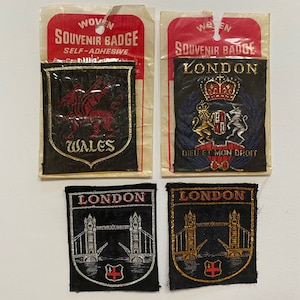 May include: Four woven souvenir badges with self-adhesive backing. The badges feature the Welsh dragon, the coat of arms of London, and two different images of Tower Bridge. The badges are black with gold and silver accents.