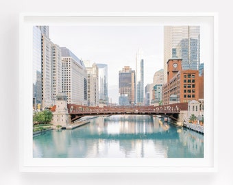 May include: A photograph of a bridge over a river in Chicago, Illinois. The bridge is made of metal and is painted red. The river is calm and reflects the buildings on the other side. The buildings are tall and modern, with a variety of colours and styles.