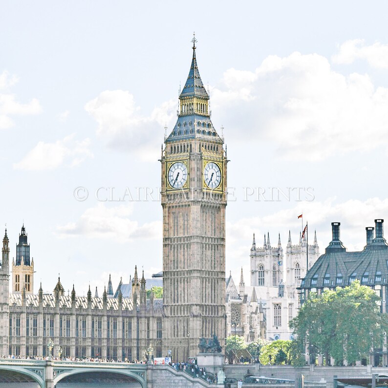 May include: A view of Big Ben, the iconic clock tower of the Houses of Parliament in London, England. The tower is a pale yellow with a dark blue roof and a clock face with Roman numerals. The tower is surrounded by other buildings, including the Houses of Parliament and Westminster Abbey.