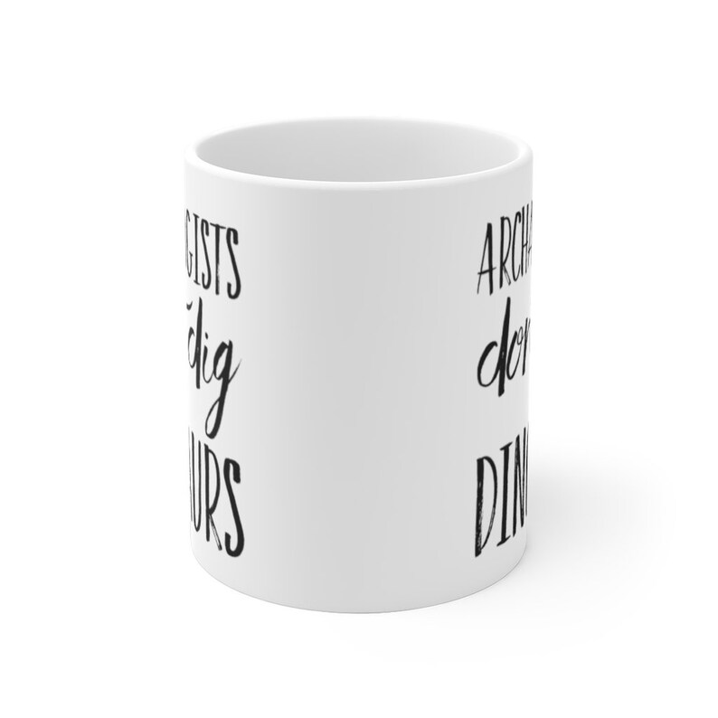 May include: White ceramic mug with black text that reads "Archaeologists dig dinosaurs".