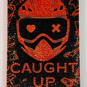 May include: A book cover with the title "CAUGHT UP" and the author's name "NAVESSA ALLEN". The cover features a black background with an orange graphic of a helmet and goggles, and the text is also orange.