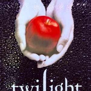 May include: A vibrant red apple cradled in two hands, set against a dark, textured background. The word "twilight" is written in white script at the bottom of the image, creating a striking contrast.